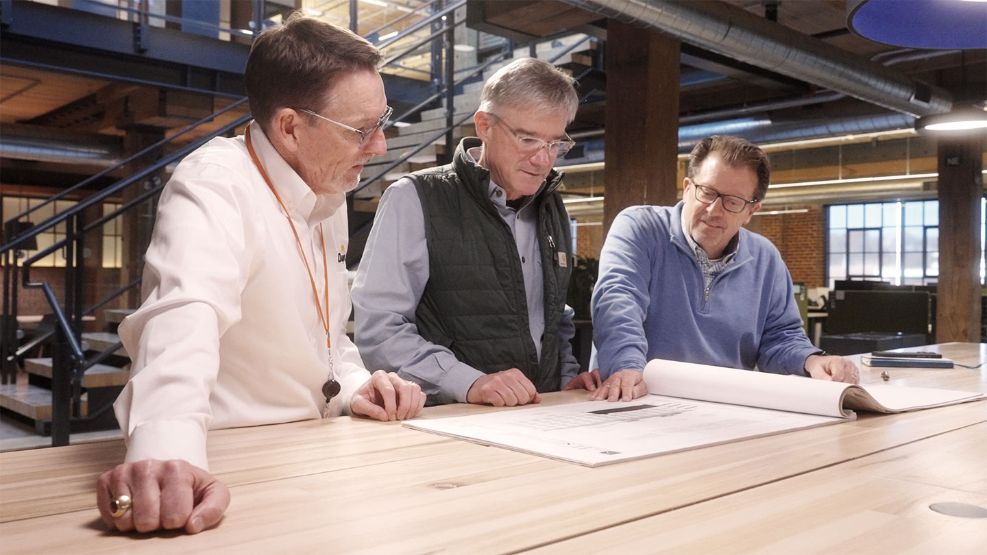 3 people looking at blueprints